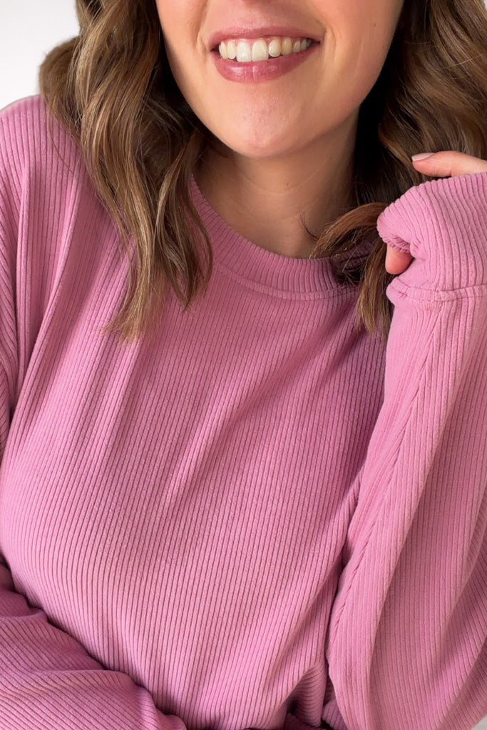 Person wearing a pink ribbed sweater with a close-up of the garment.