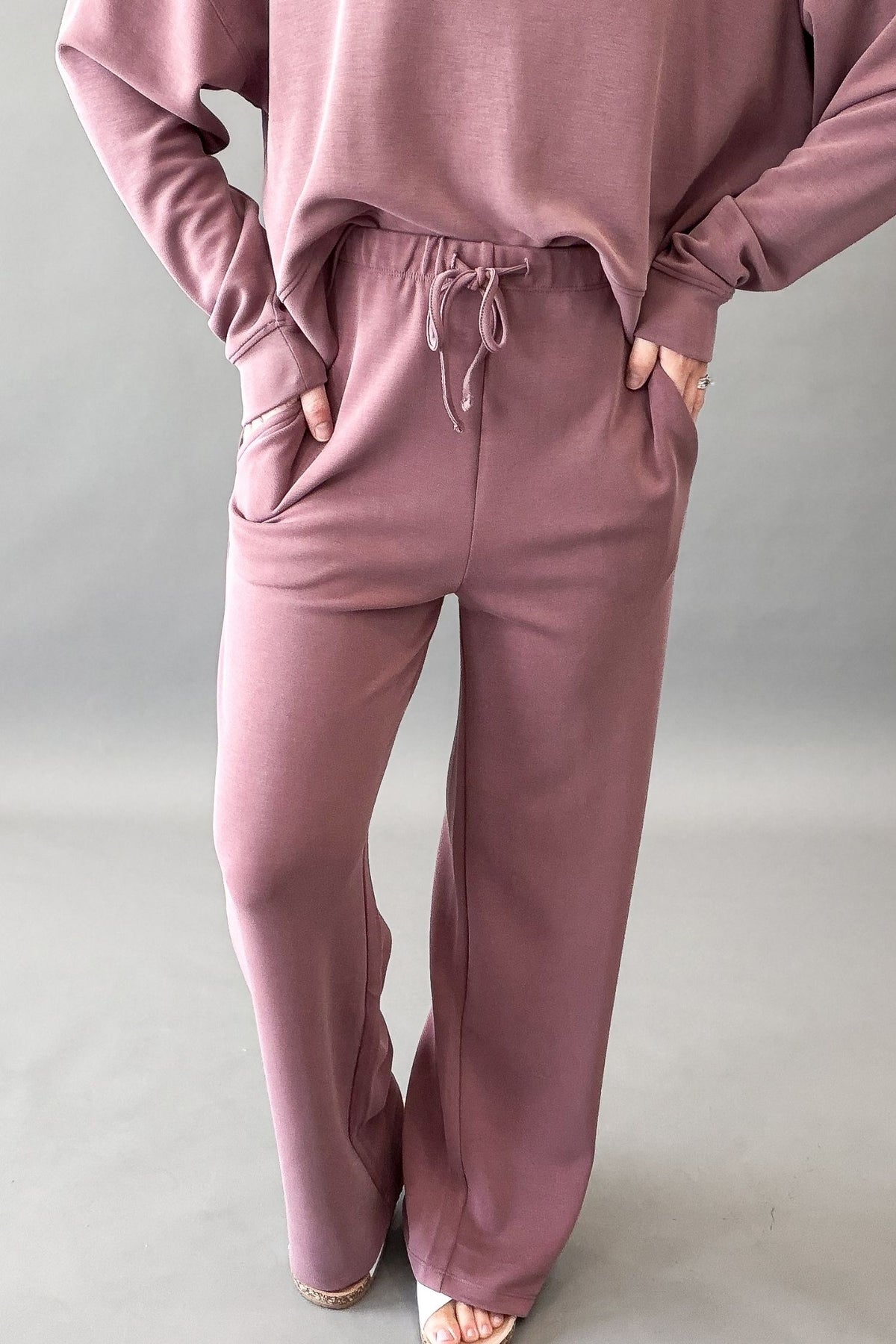woman wearing a rose pant and sweatshirt set showing side pockets