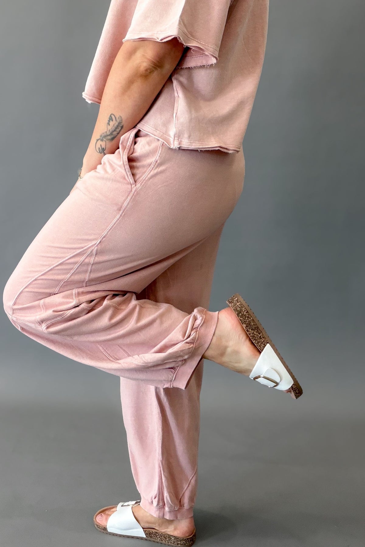woman wearing a pink lounge set showing the side pocket and back details