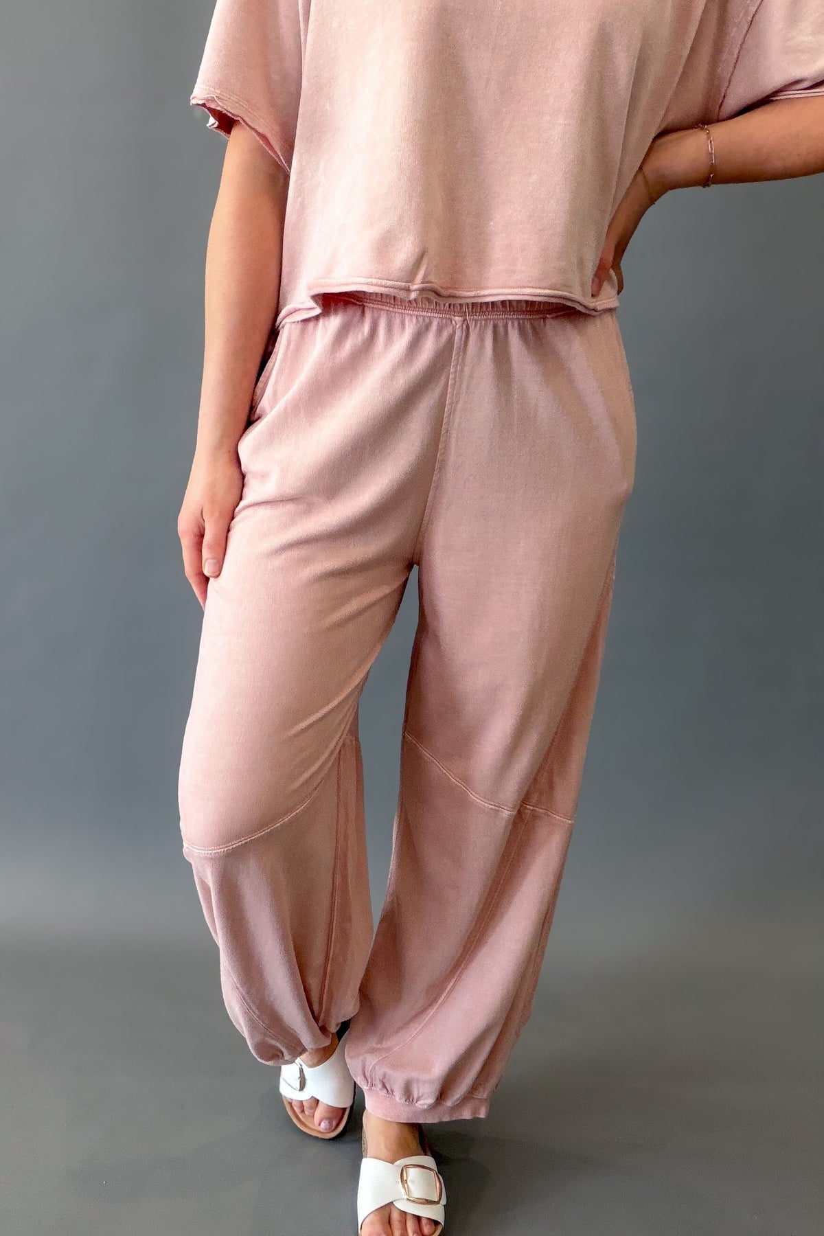 woman wearing a pink terry jogger set and white sandals