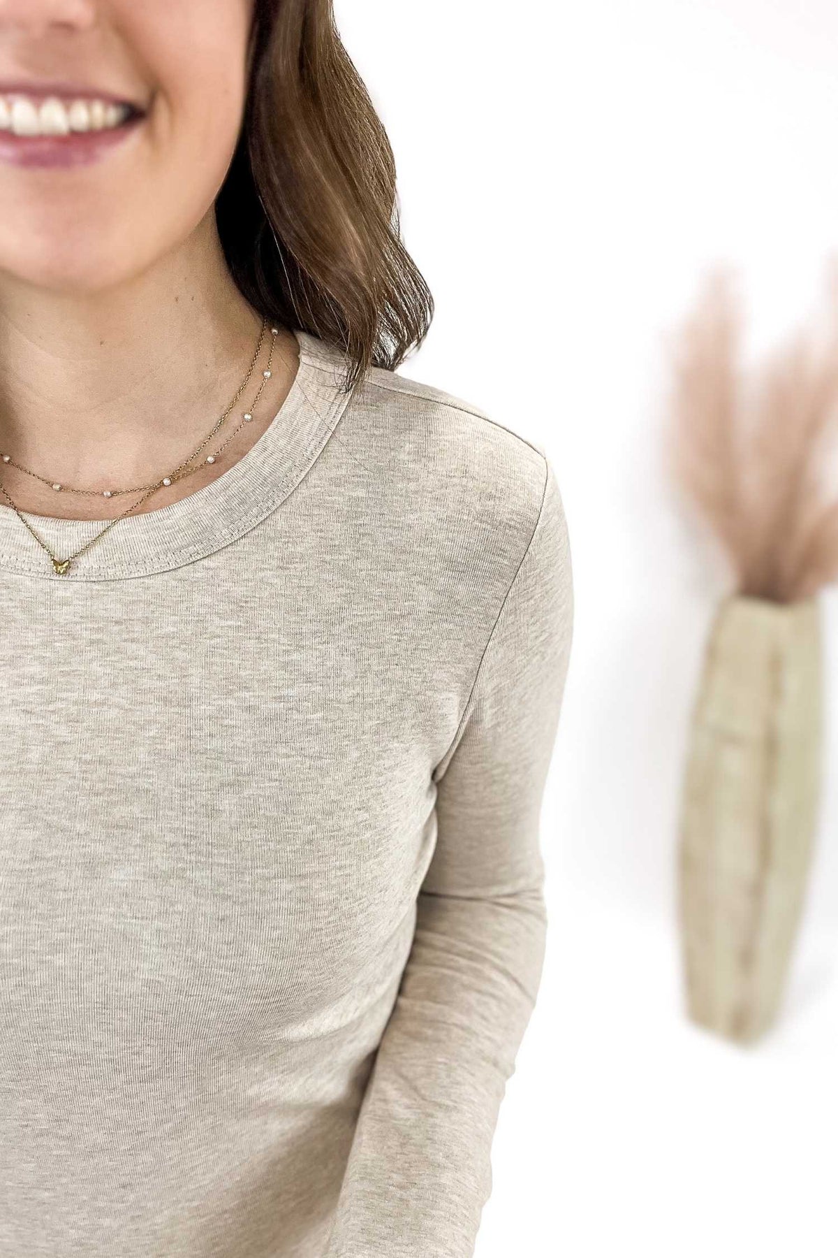 Woman wearing a oatmeal long-sleeve shirt with a blurred background
