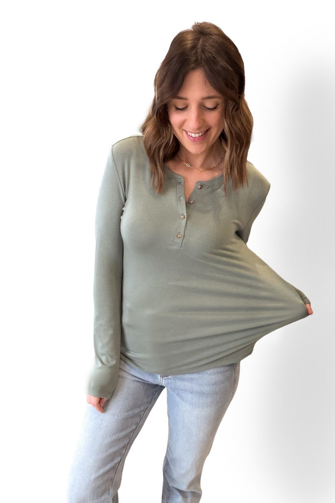 Woman wearing a green long-sleeve top and light blue jeans on a white background
