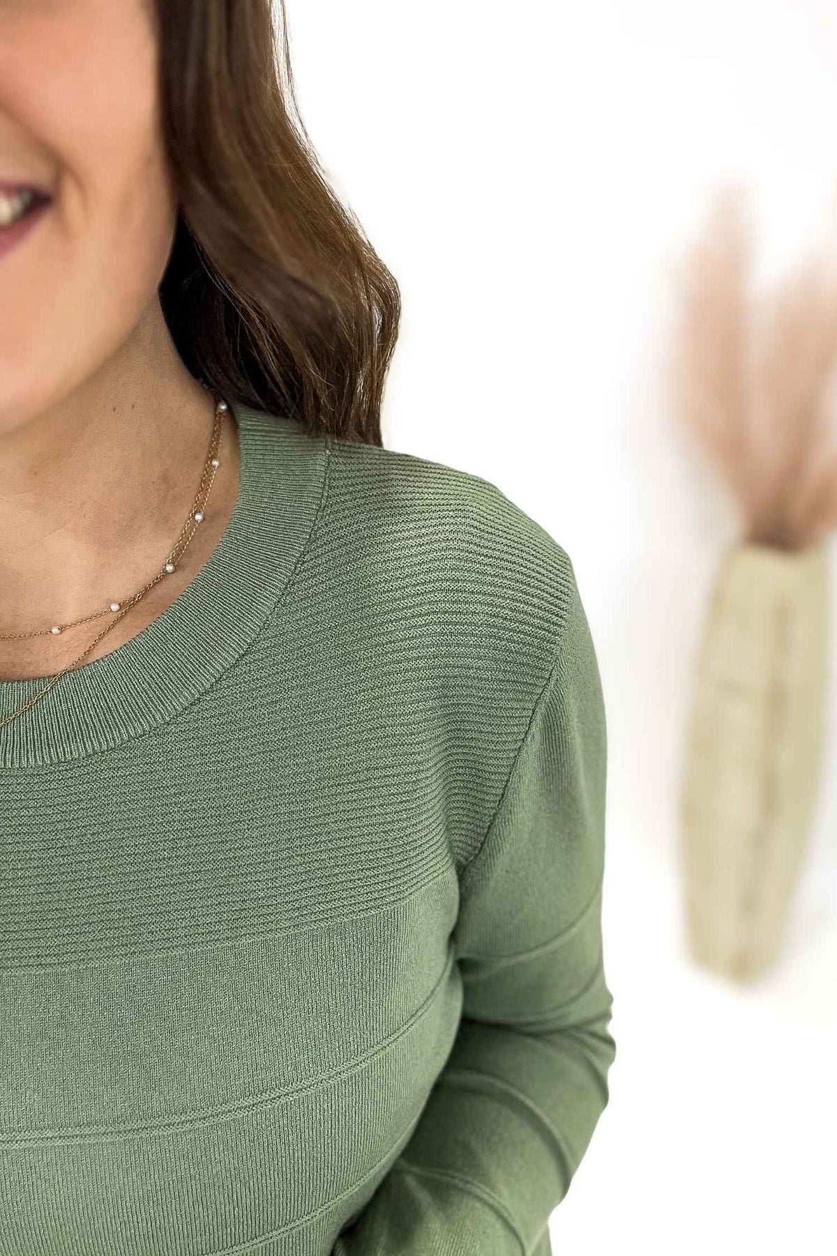 Woman wearing a green sweater with a blurred background