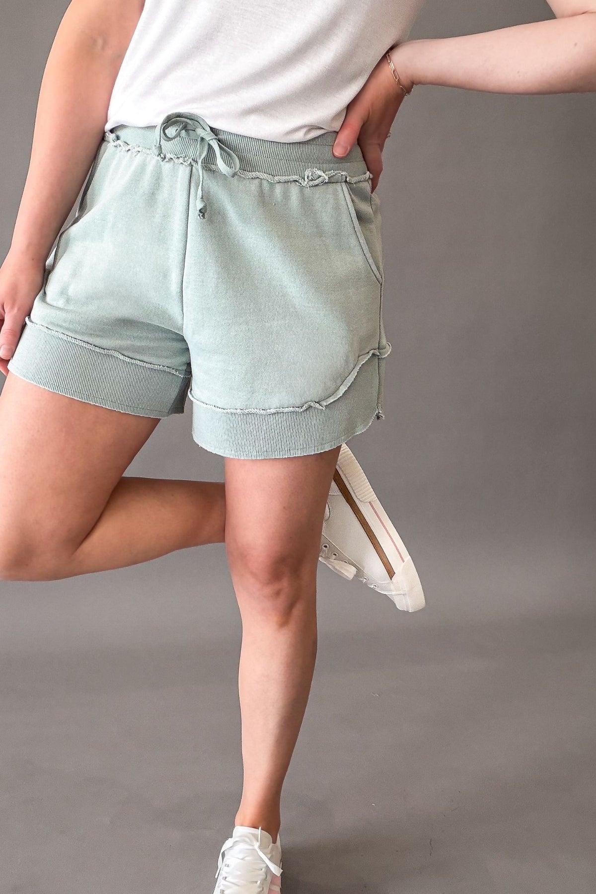 woman wearing french terry shorts with sneakers on a grey background