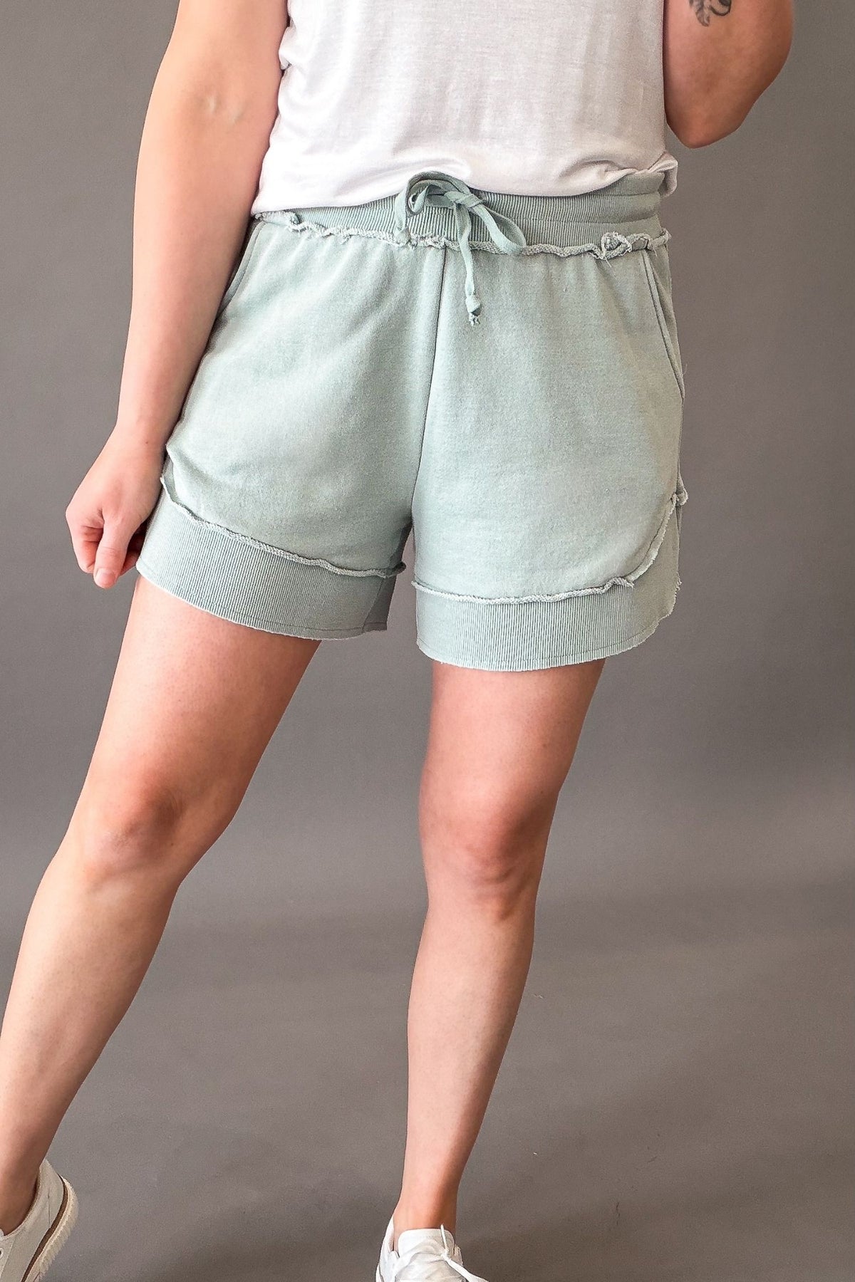 woman wearing french terry shorts with sneakers on a grey background