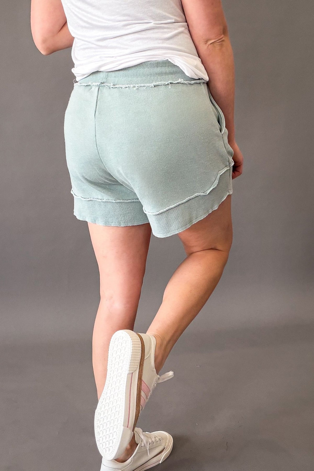 woman wearing french terry shorts with sneakers on a grey background showing back details