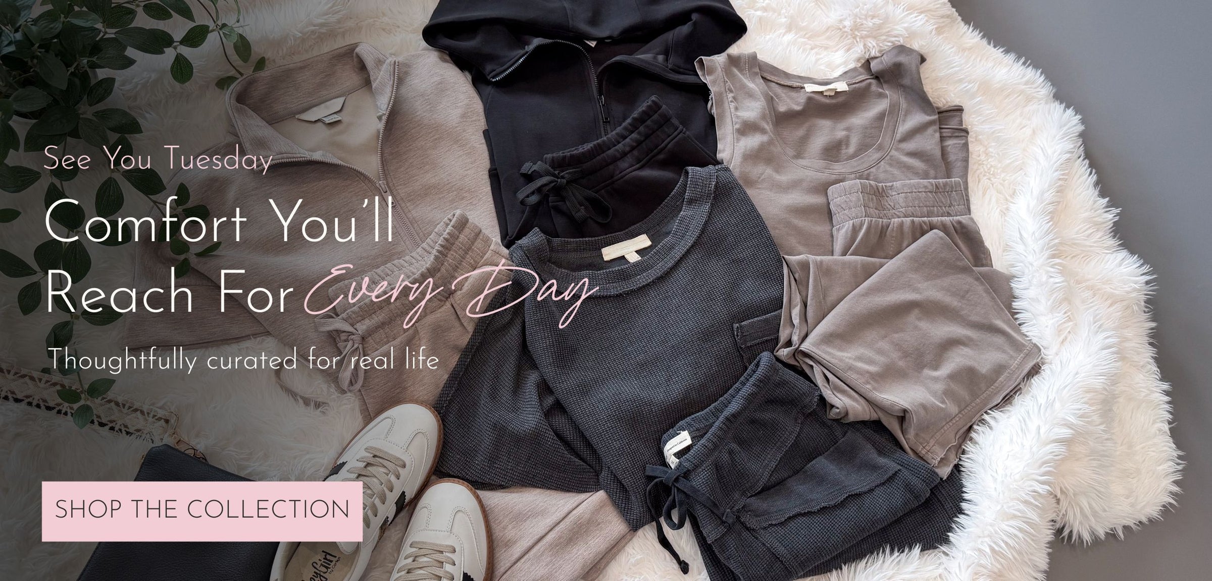 A styled flat lay of folded apparel and shoes on a white faux-fur surface. Visible items include a black top, a taupe sleeveless top, a dark gray T-shirt, shorts, and light beige pants, with white sneakers partly visible.