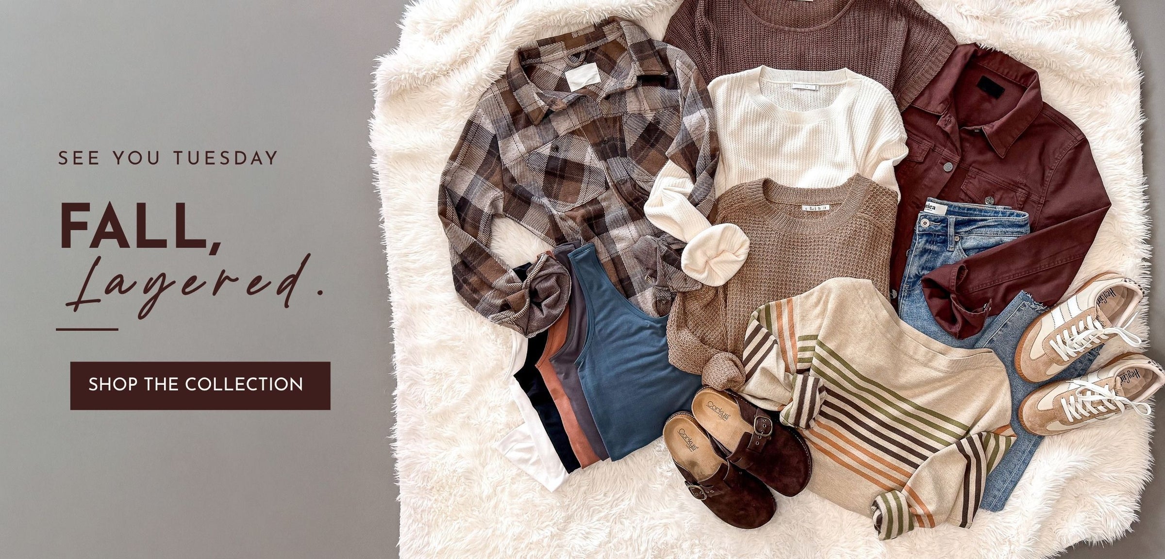 A styled flat lay of fall clothing on a white faux-fur surface, including a plaid shirt, white tee, brown shirt, jeans, striped sweater, boots, and shoes, with text reading 'SEE YOU TUESDAY FALL, Layered. SHOP THE COLLECTION' on the left.