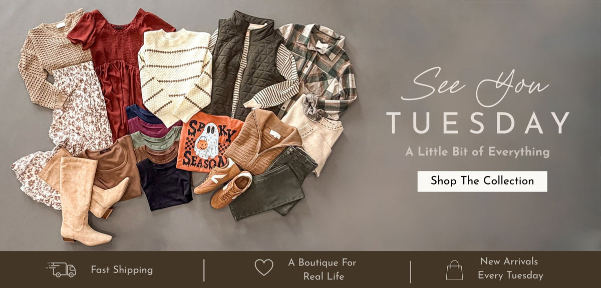 A flat lay of assorted clothing and accessories arranged on a dark gray background, with promotional text reading 'See You TUESDAY' and 'Shop The Collection.' The garments include multiple tops, a jacket, patterned pieces, boots, and shoes in muted earthy tones.