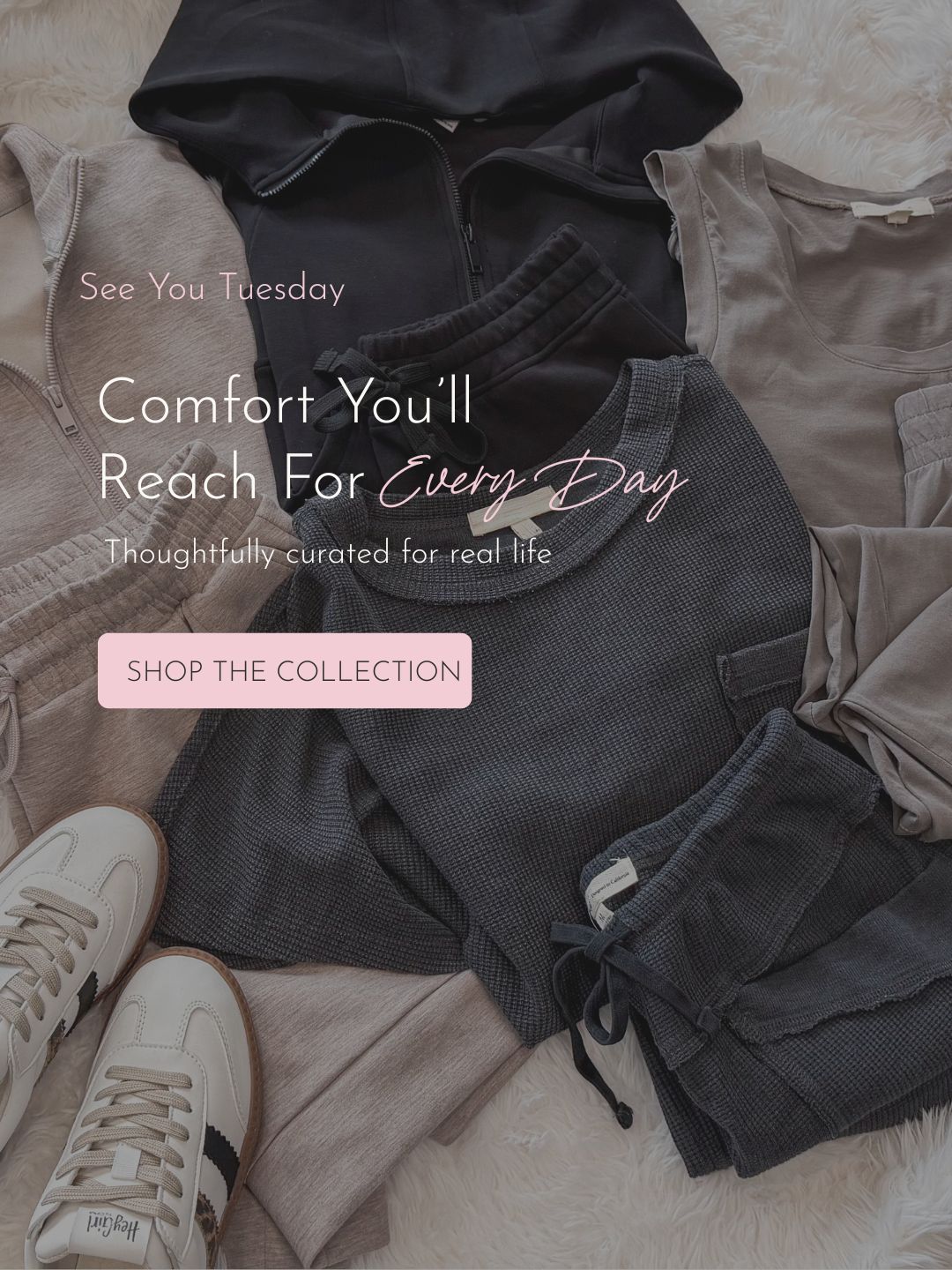 A styled flat lay of folded clothing and shoes on a soft cream surface. The garments include a black zip-up hoodie, a dark gray ribbed top and shorts set, and light beige/taupe pieces.