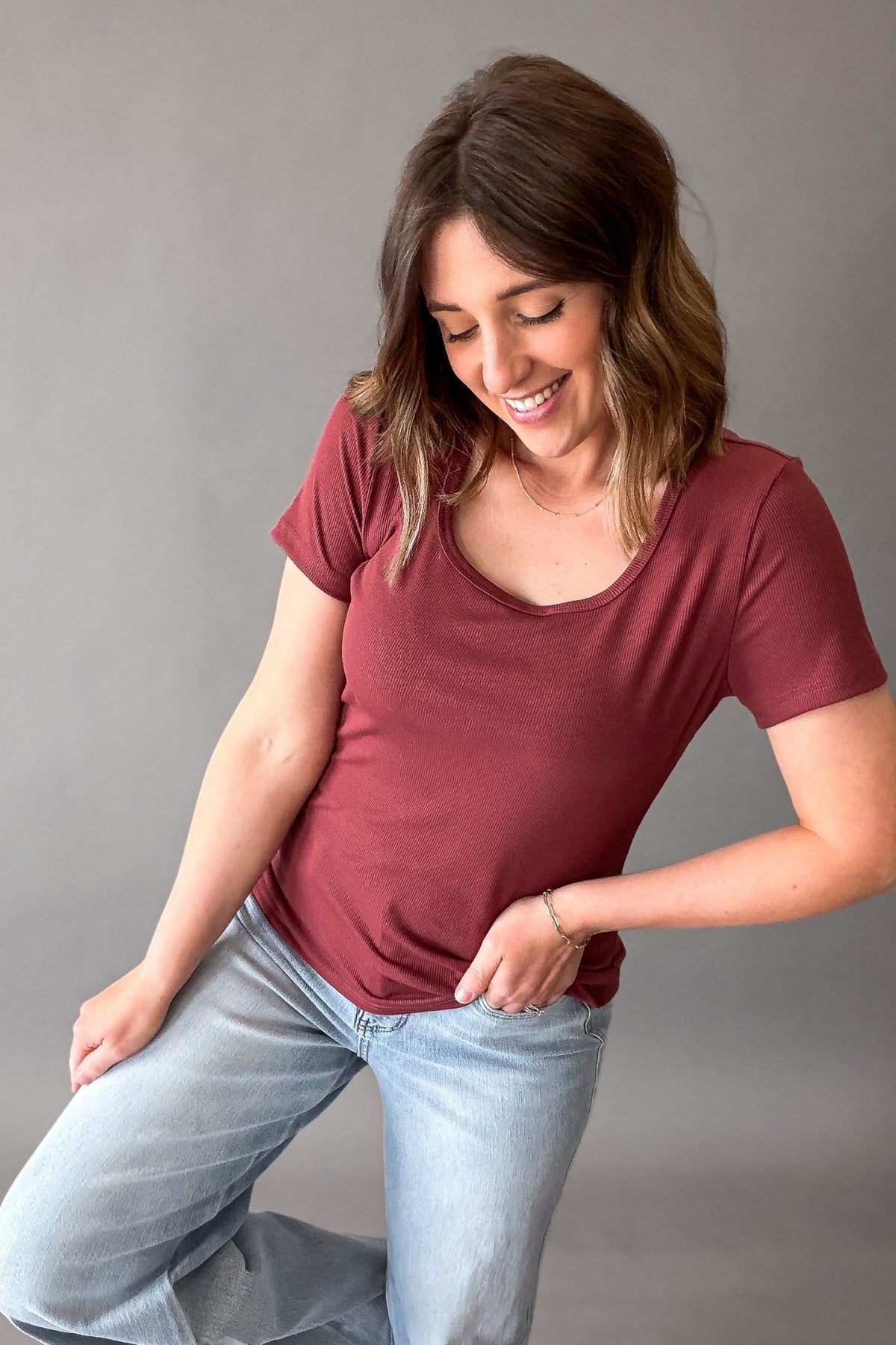 woman wearing a scoop neck garnit tee untucked with judy blue light wash jeans