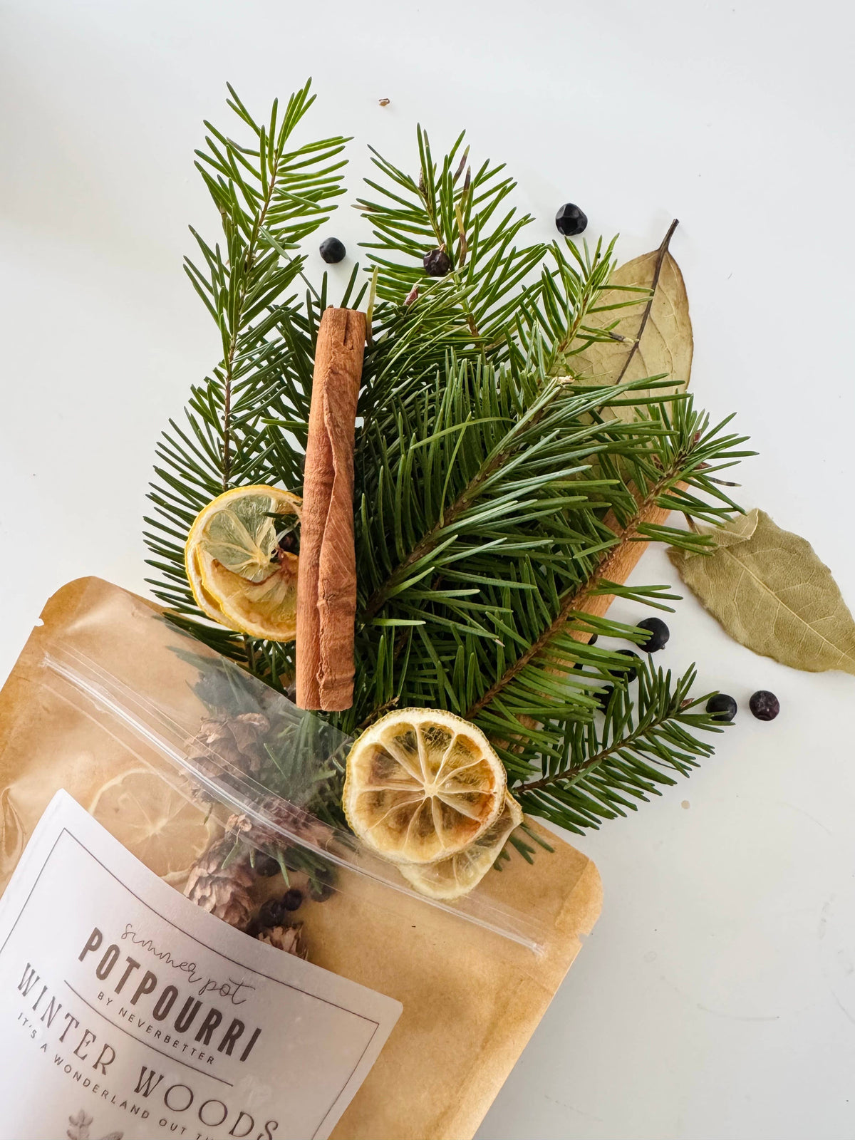 Winter wood potpourri with cinnamon stick, pine branches, and dried lemons on a white background.