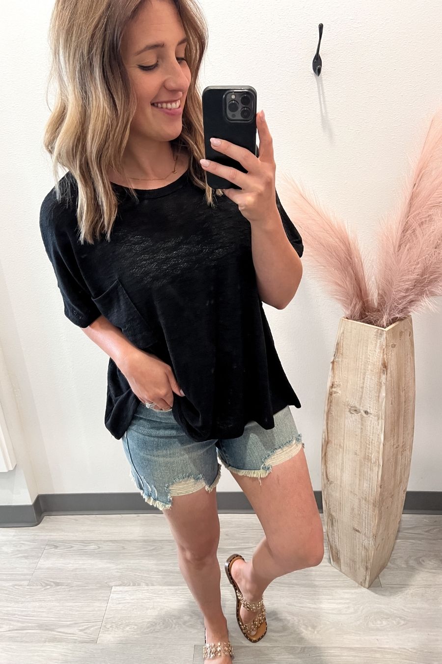 Woman wearing a black slub short sleeve top paired with denim shorts