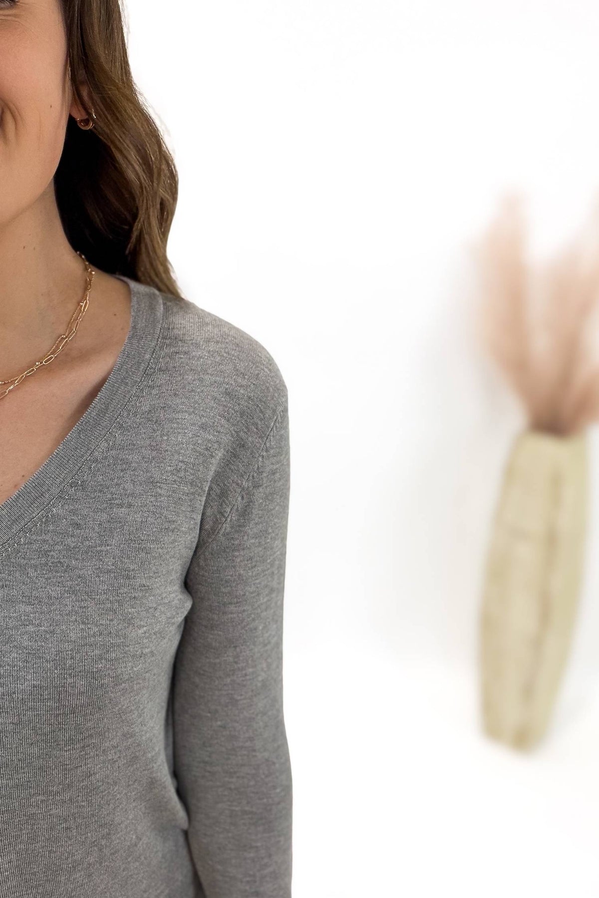 Woman wearing a gray long-sleeve top with a blurred background