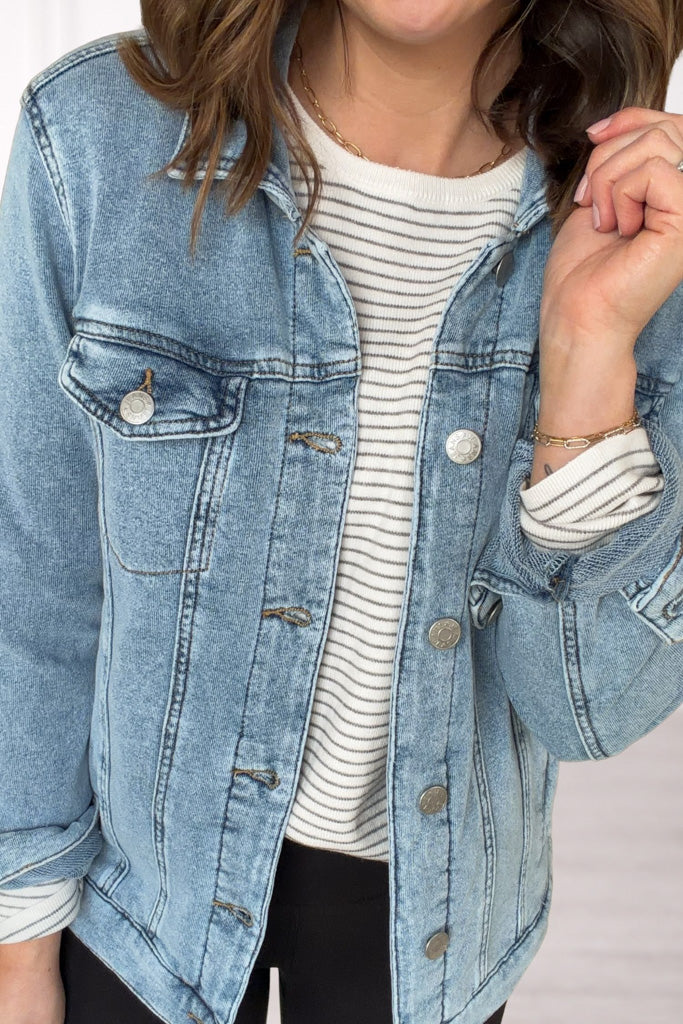 Person wearing a light blue denim jacket over a striped shirt