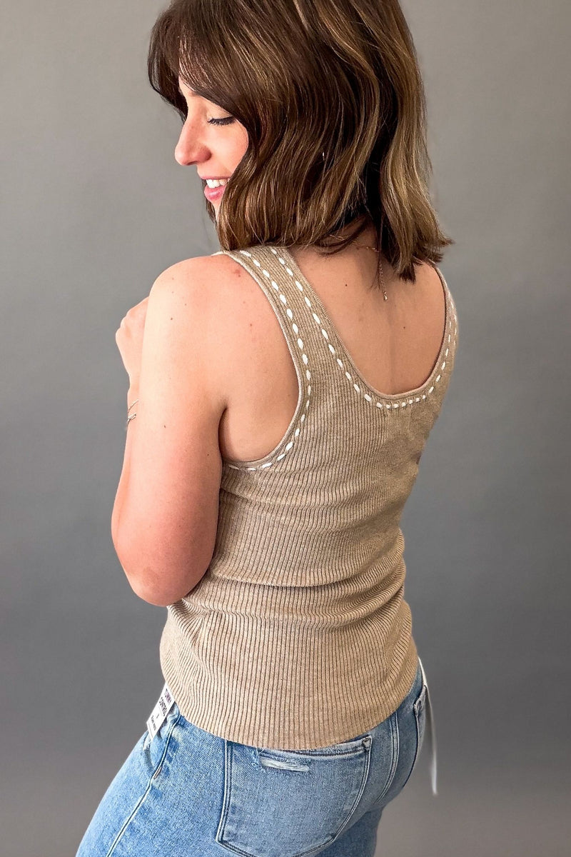 Woman wearing a soft mocha ribbed sweater tank with white contrast stitching styled with light wash RISEN jeans.