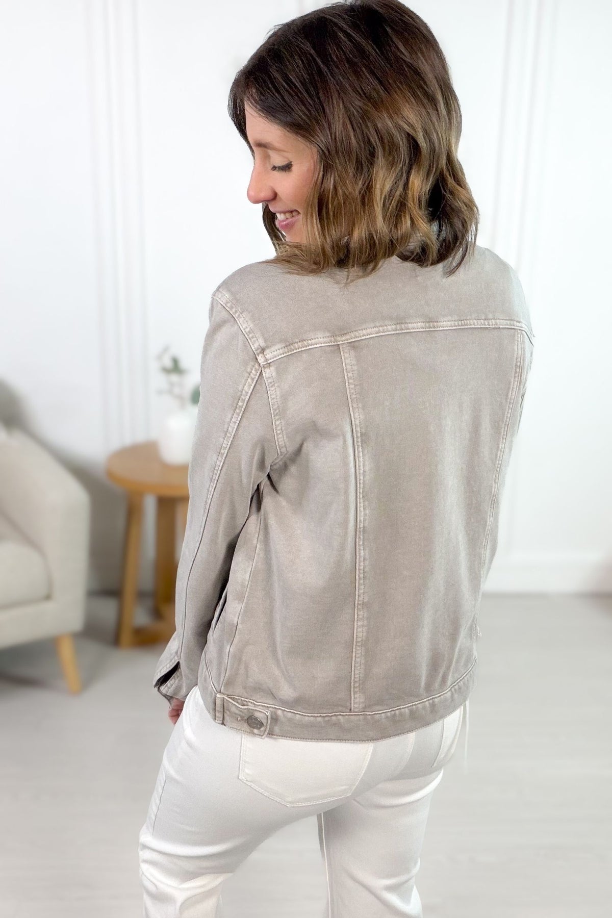 Woman wearing a light stone denim jacket showing the back details.