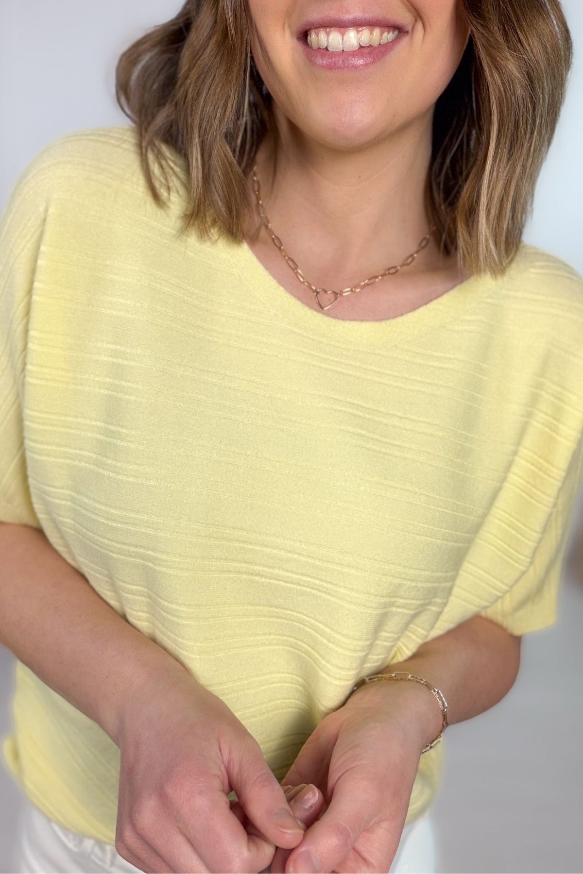 Soft yellow ribbed short sleeve tee styled with white denim jeans showing the close up details