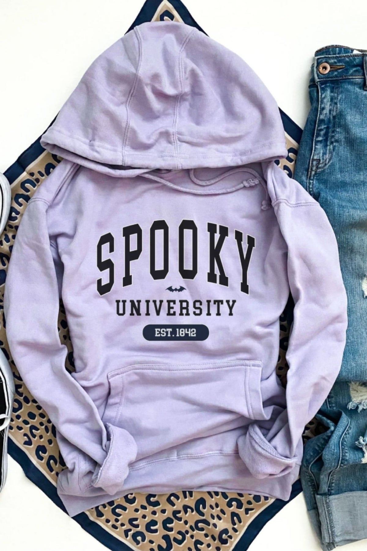 Light purple hoodie with 'Spooky University' text on a leopard print and denim background