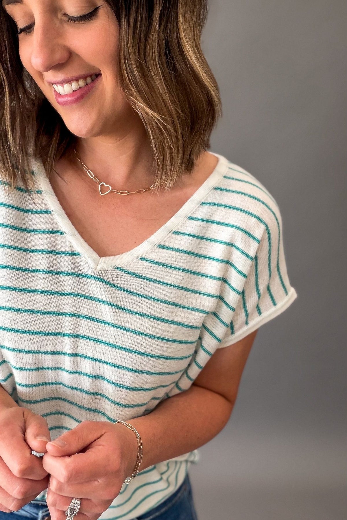Woman wearing a teal striped shirt with a neutral background