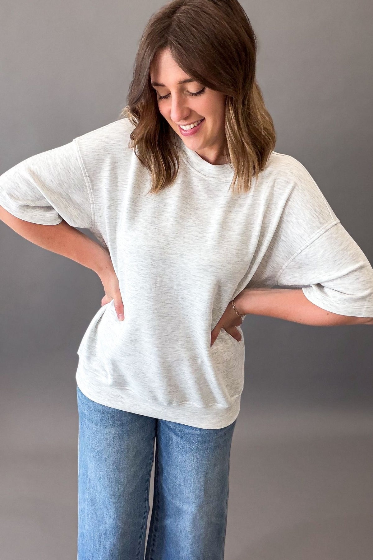 woman wearing a relaxed super soft heather grey short sleeve with blue jeans on a charcoal background