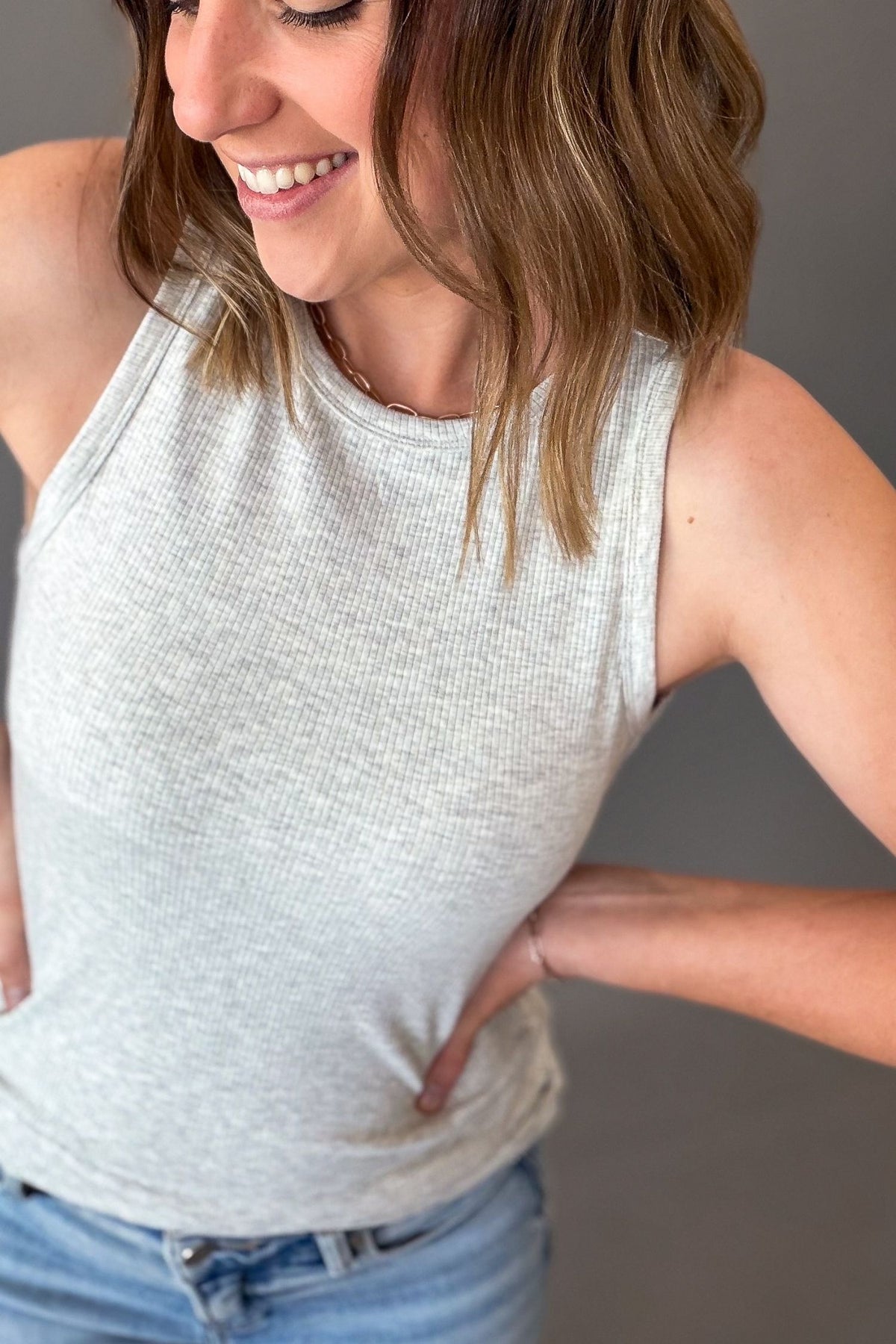woman wearing a soft and stretchy ribbed layering tank in heather grey with blue jeans