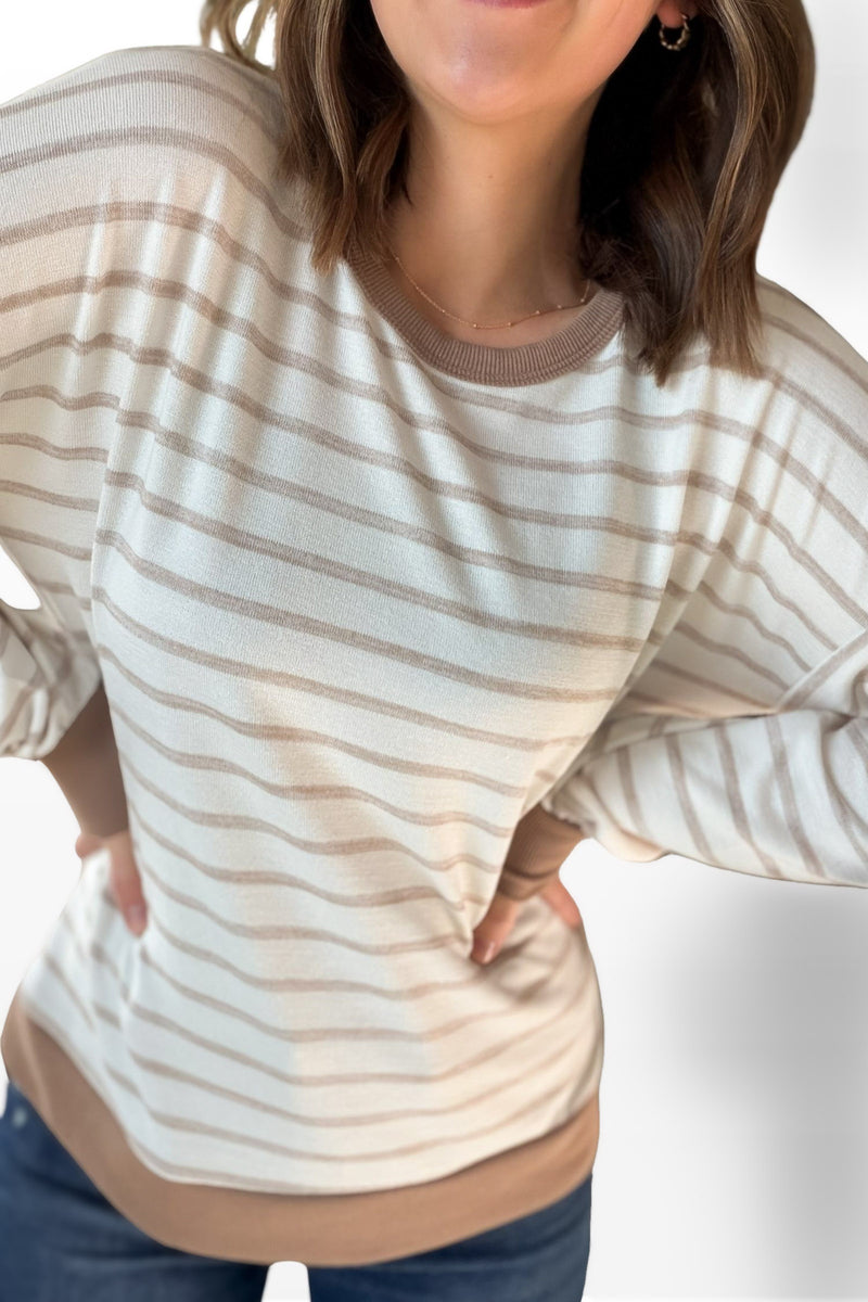 Person wearing a beige and white striped sweater with a neutral background