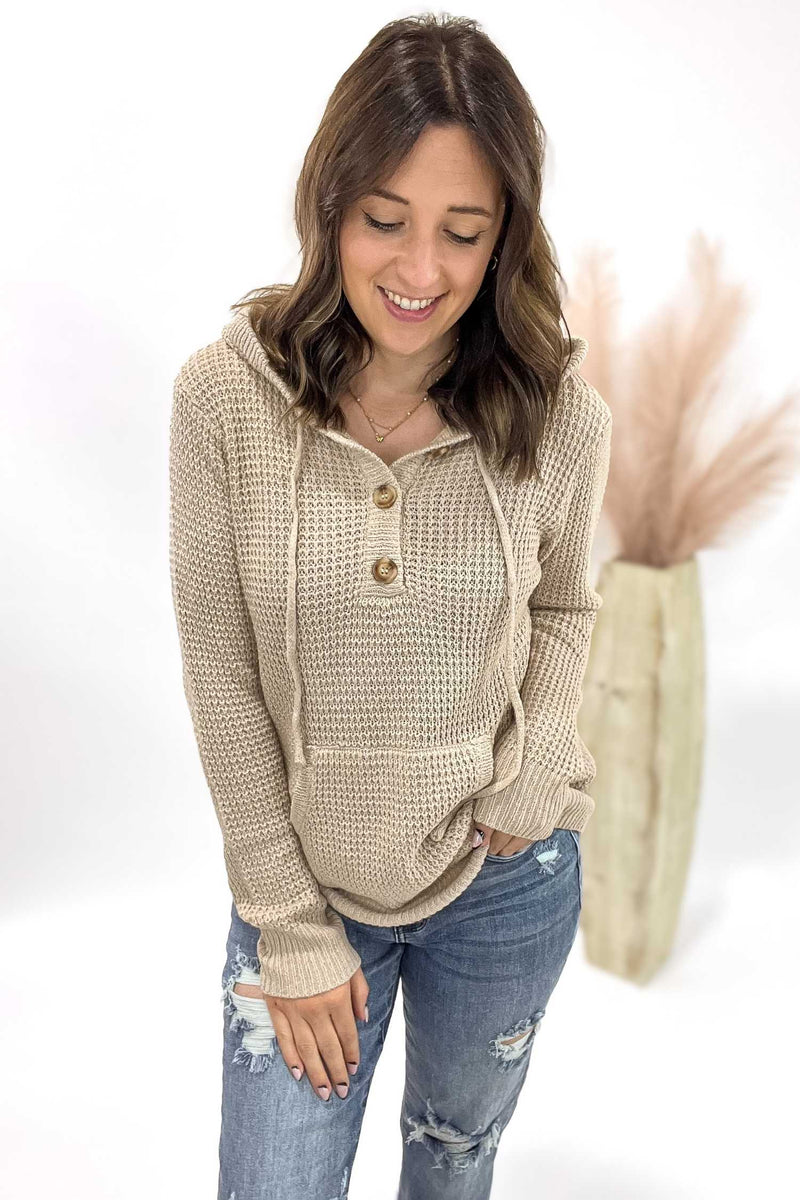 Woman wearing a beige knitted sweater with a hood on a white background