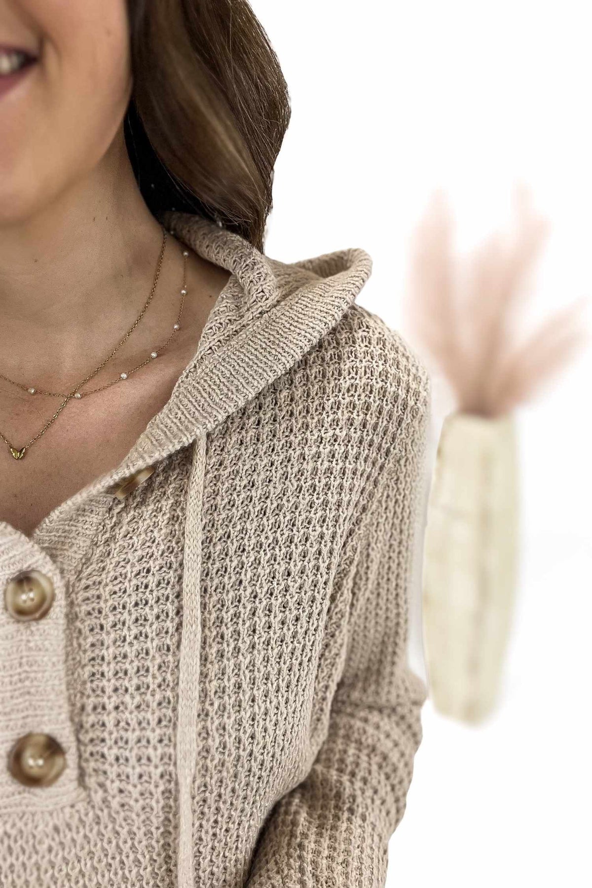 Woman wearing a beige knitted cardigan with a blurred background