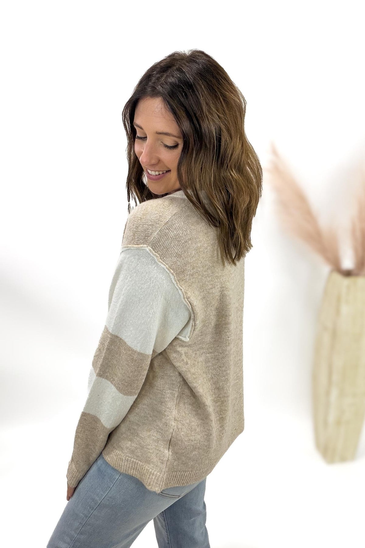 Woman wearing a beige sweater with a large gray patch on a white background
