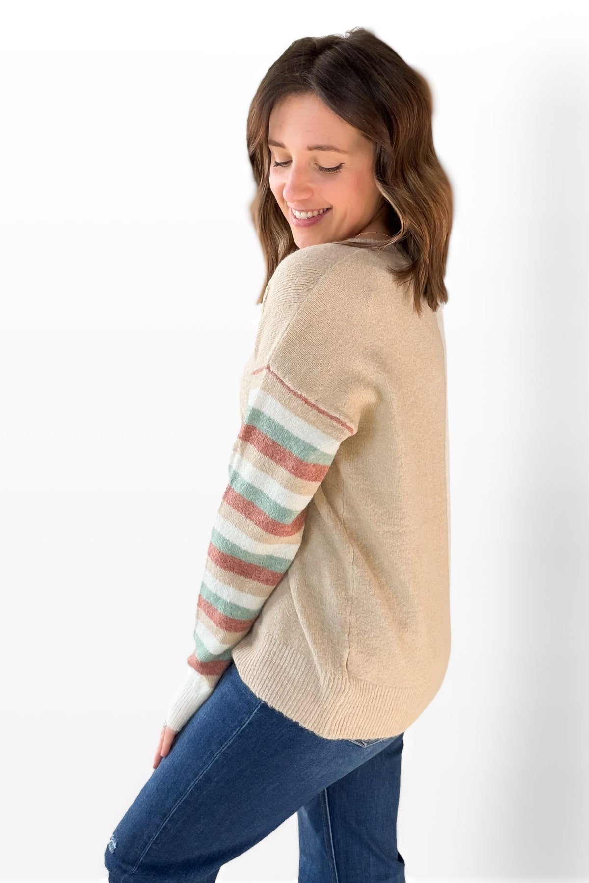 Woman wearing a beige sweater with colorful stripes on a white background