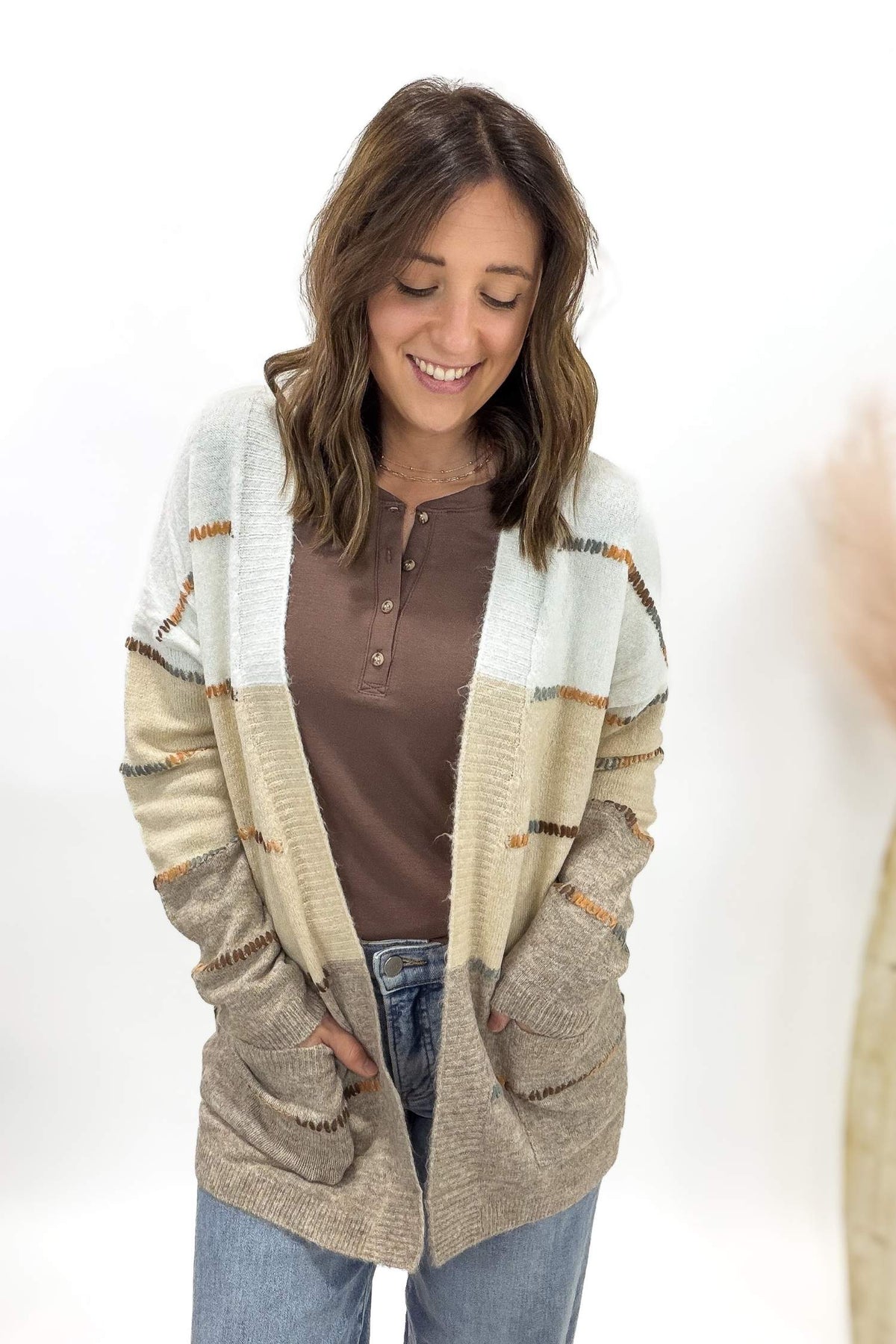 Woman wearing a patterned cardigan over a brown shirt on a white background