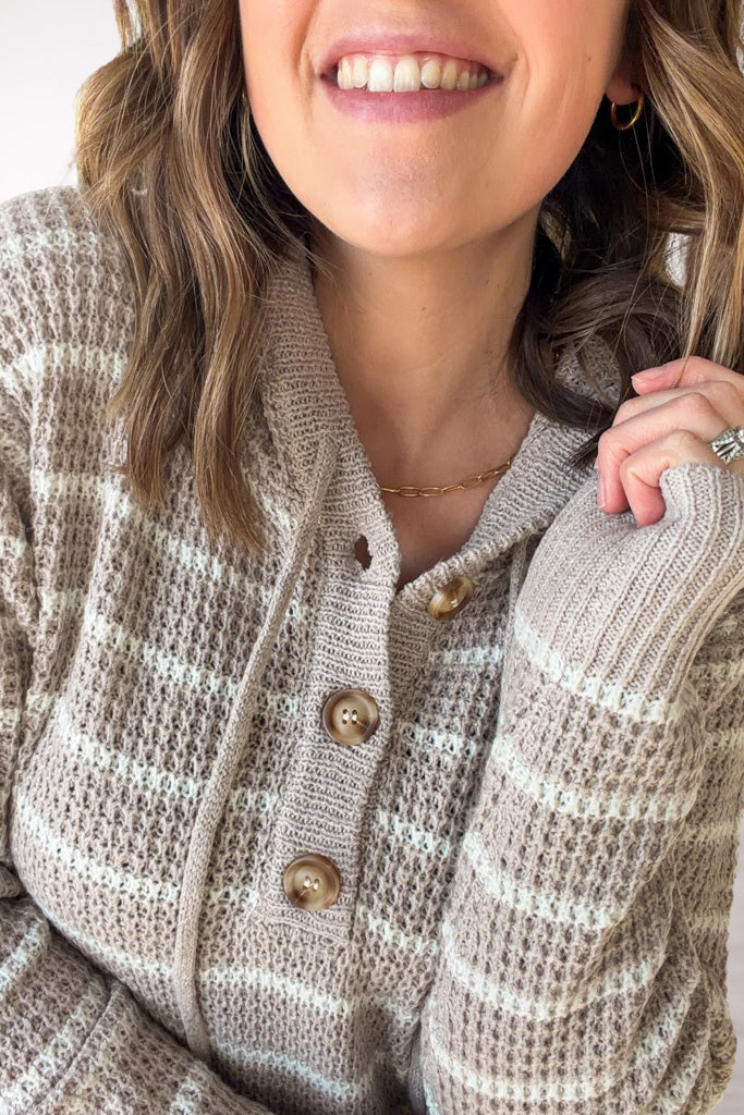Close-up of a person wearing a striped  sweater with a neutral background