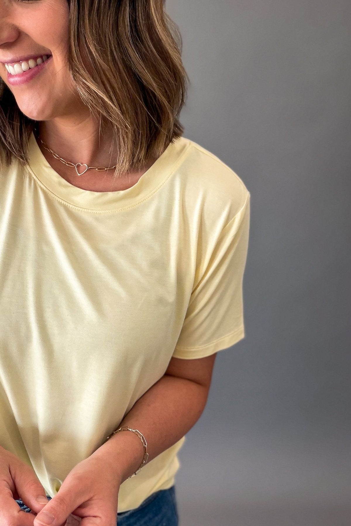 Woman wearing a light yellow t-shirt against a gray background