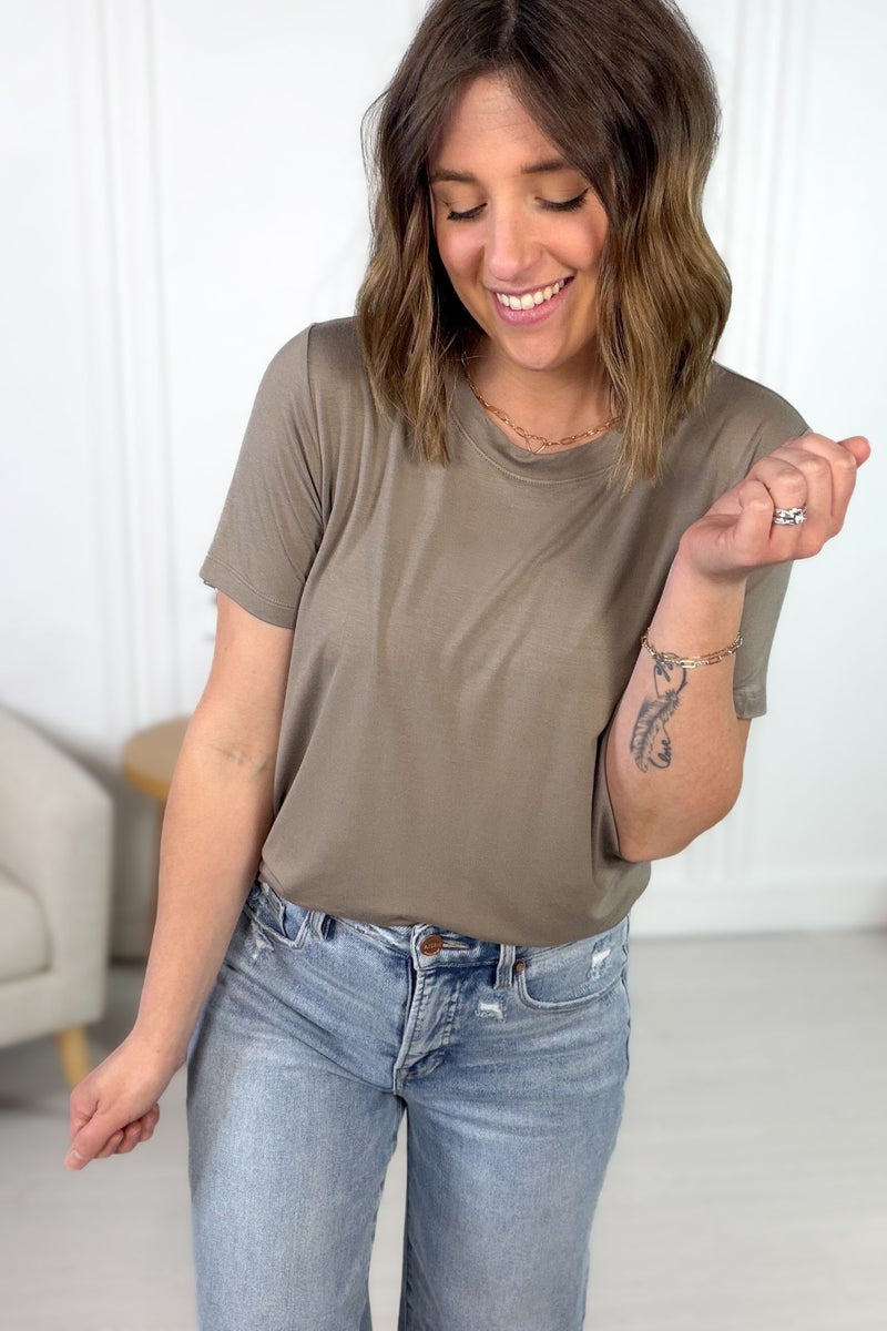 Woman wearing a moss basic t-shirt and blue jeans indoors.