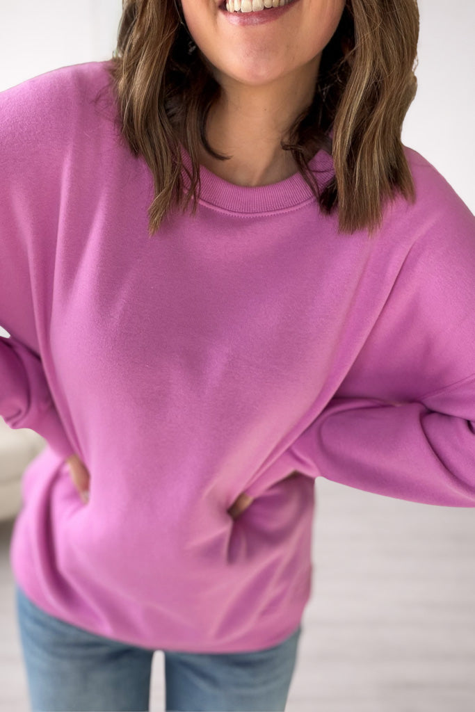 Person wearing a mauve sweatshirt with a plain background showing the sweatshirt details