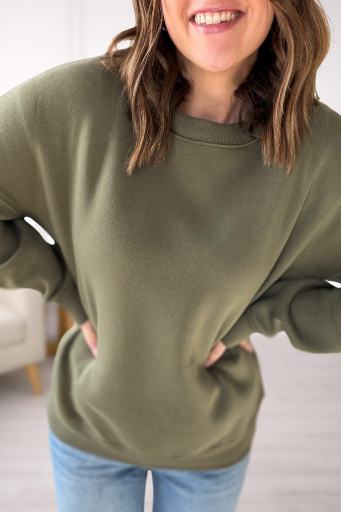 Person wearing a green sweatshirt with a blurred background