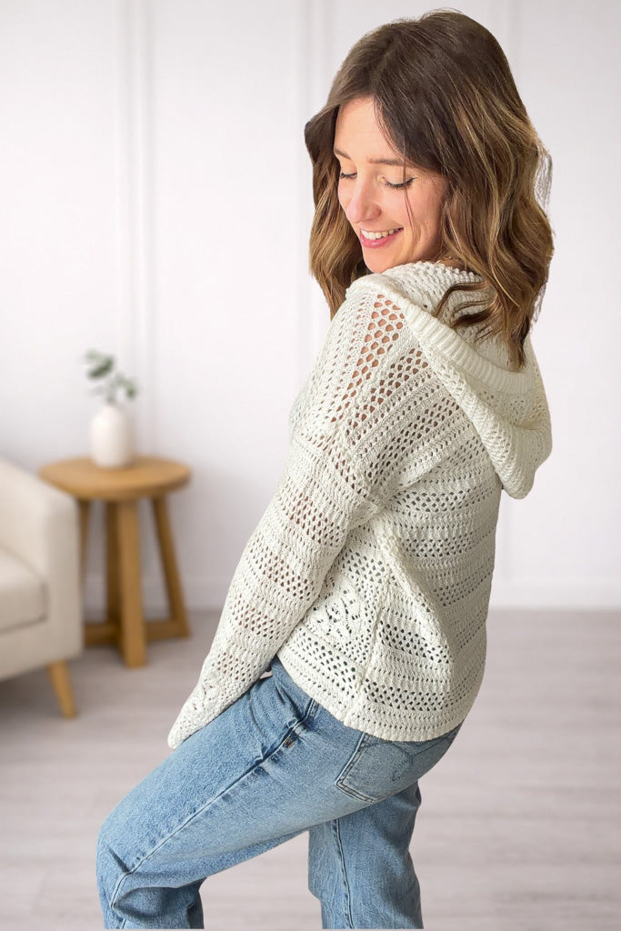 Side view of lightweight white crochet hoodie with v-neck and button detail.