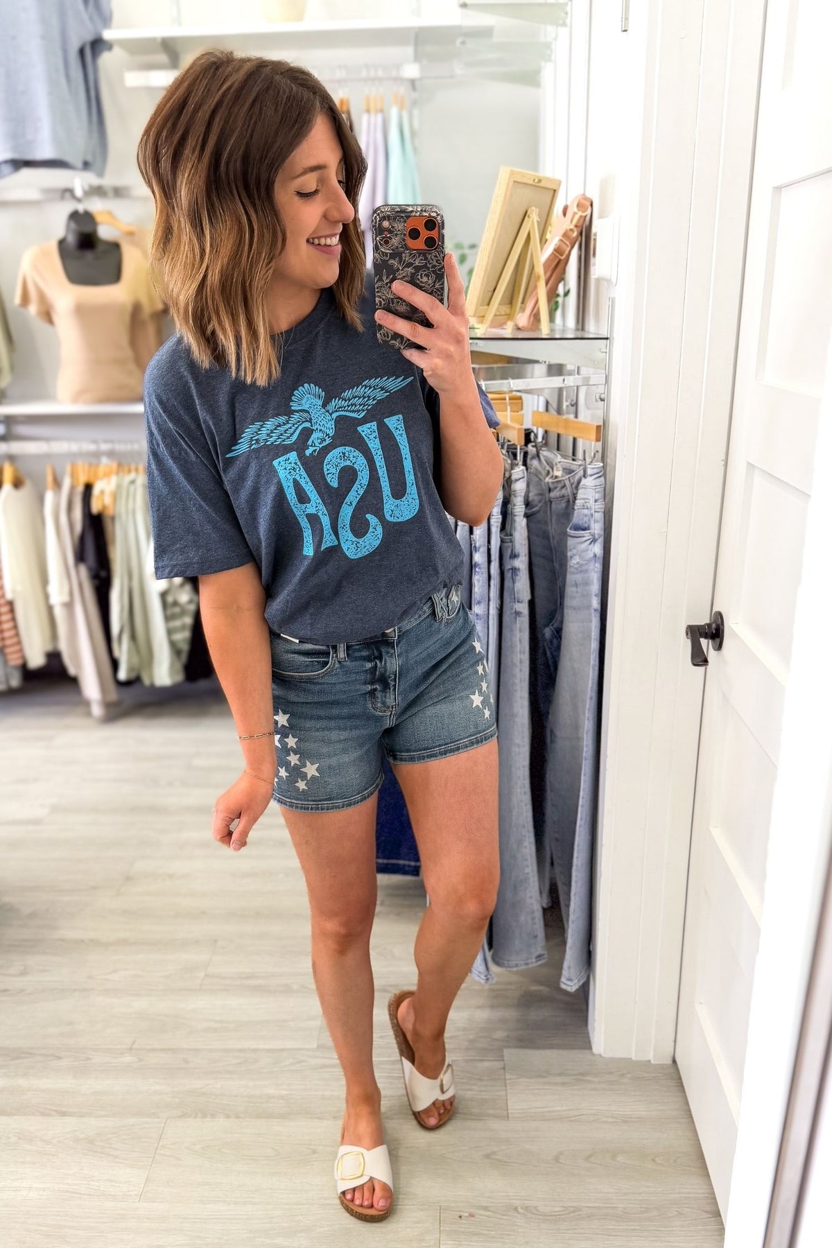 Woman taking a selfie wearing a navy vintage USA eagle graphic tee with distressed light blue screen printed graphic and denim shorts