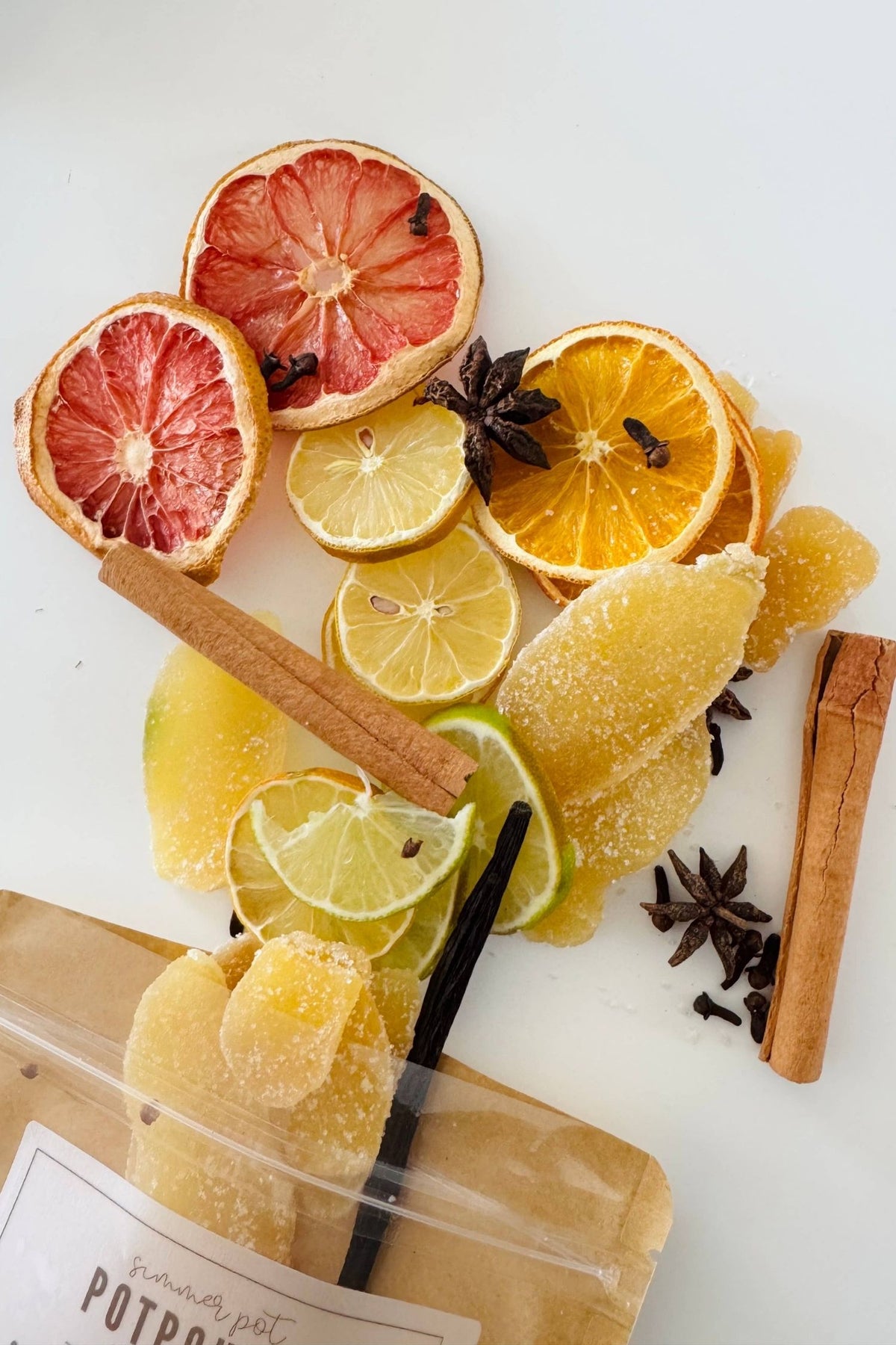 Dried simmer pot potpourri on a white background containing, Crystallized ginger, oranges, lemons, limes, grapefruit, cinnamon, star anise, cloves + vanilla bean (all natural, high quality)