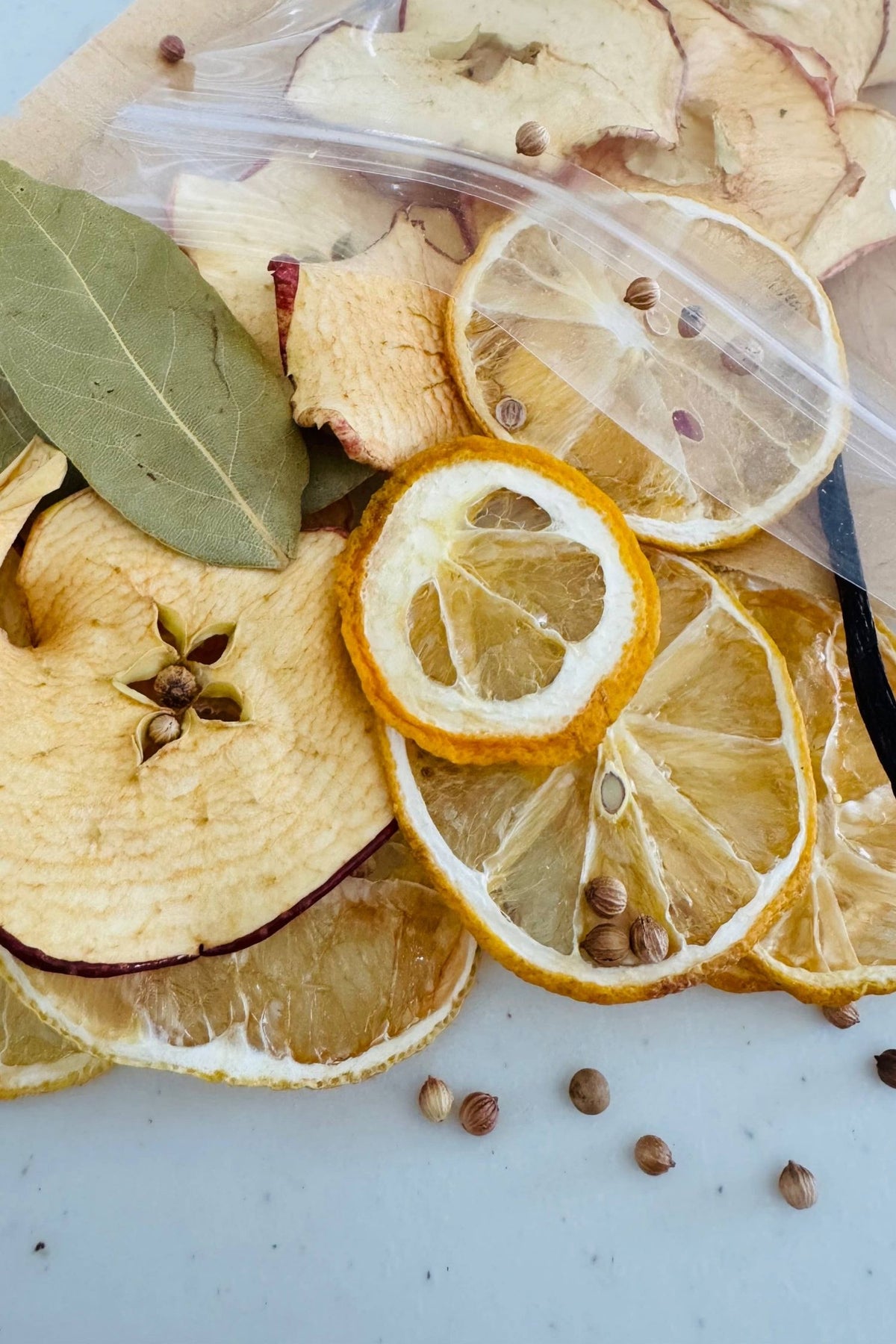 Dried lemon slices, apple pieces, and bay leaves on a white surface.