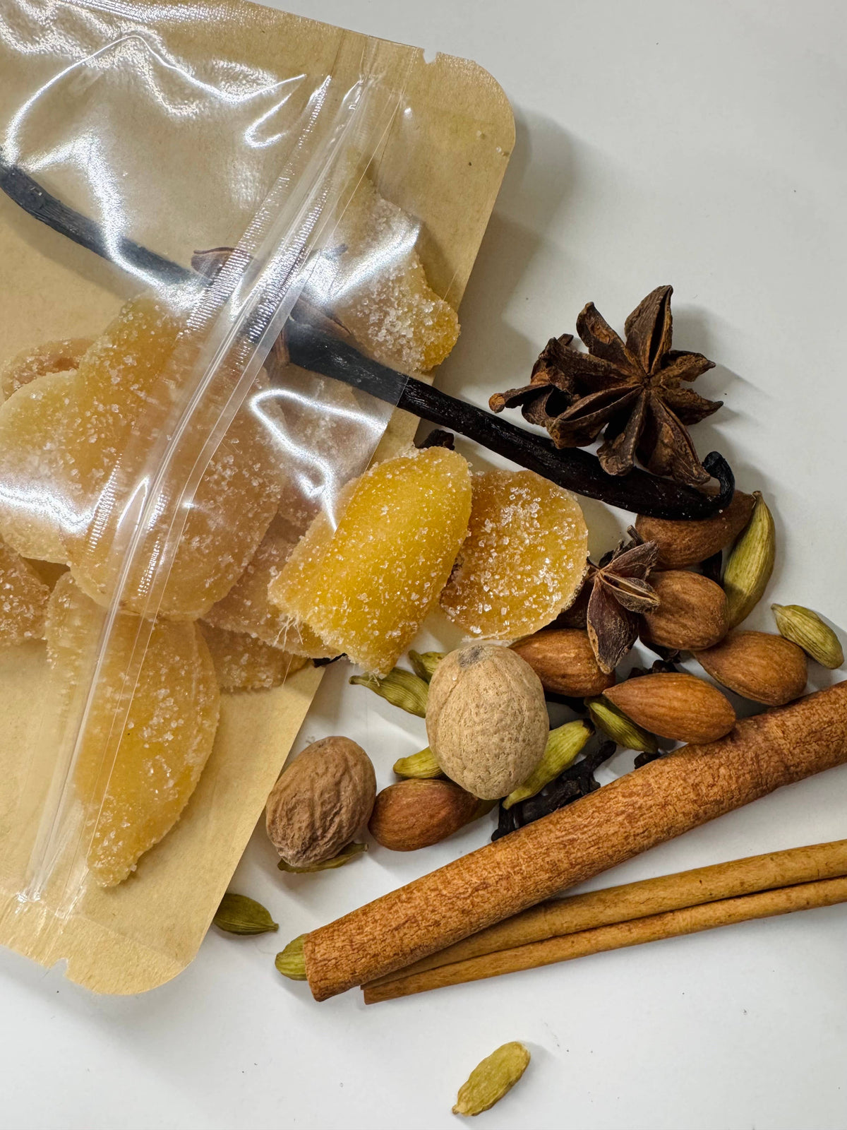 Spices and dried fruits on a white surface with a clear plastic bag.