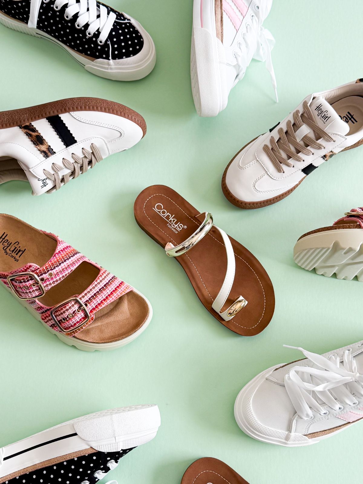 Corkys flatlay of sneakers and sandals on a green background.