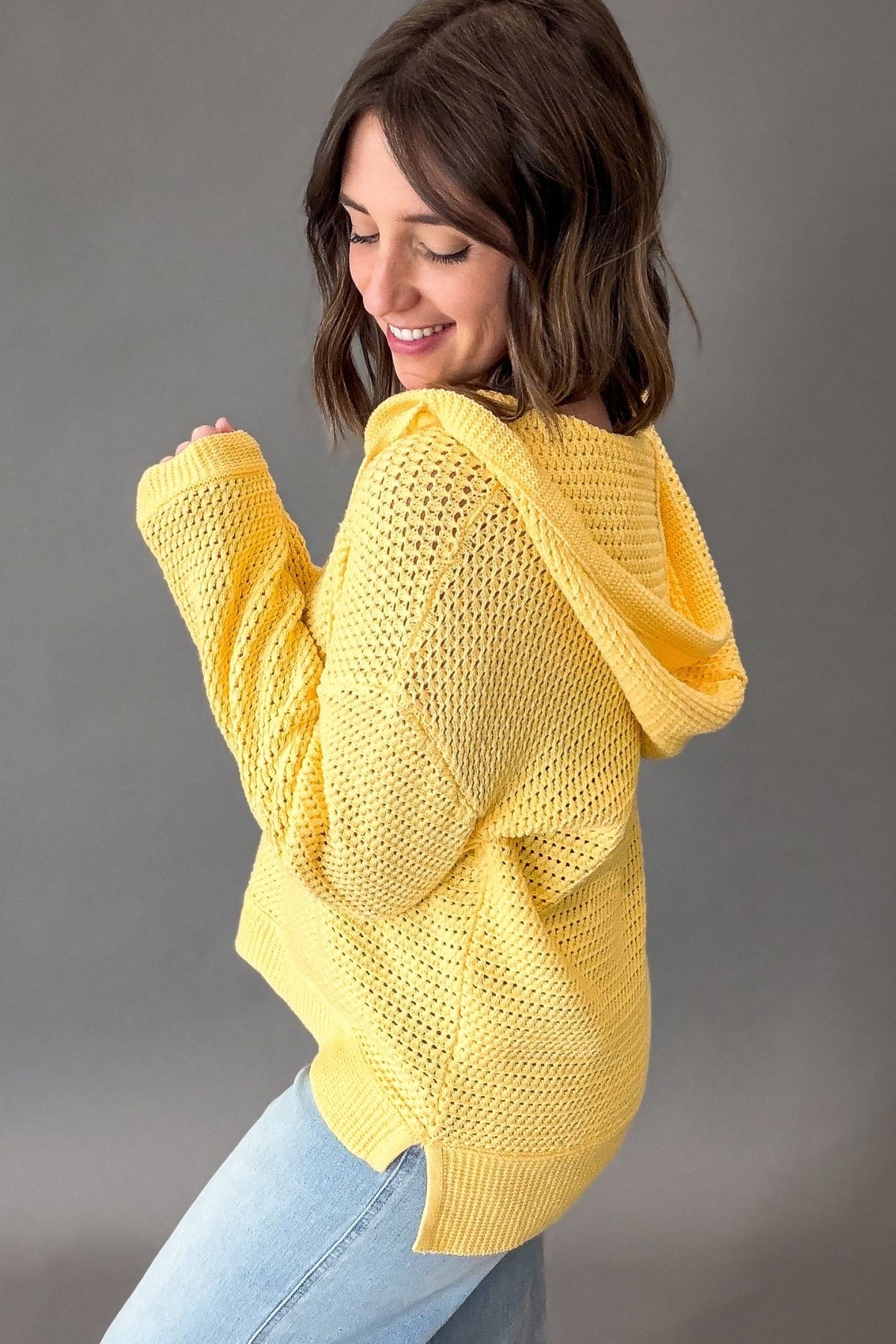 Woman wearing a yellow knitted sweater against a gray background