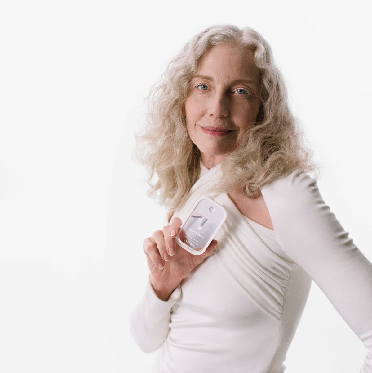 Woman holding a white electronic device against a white background