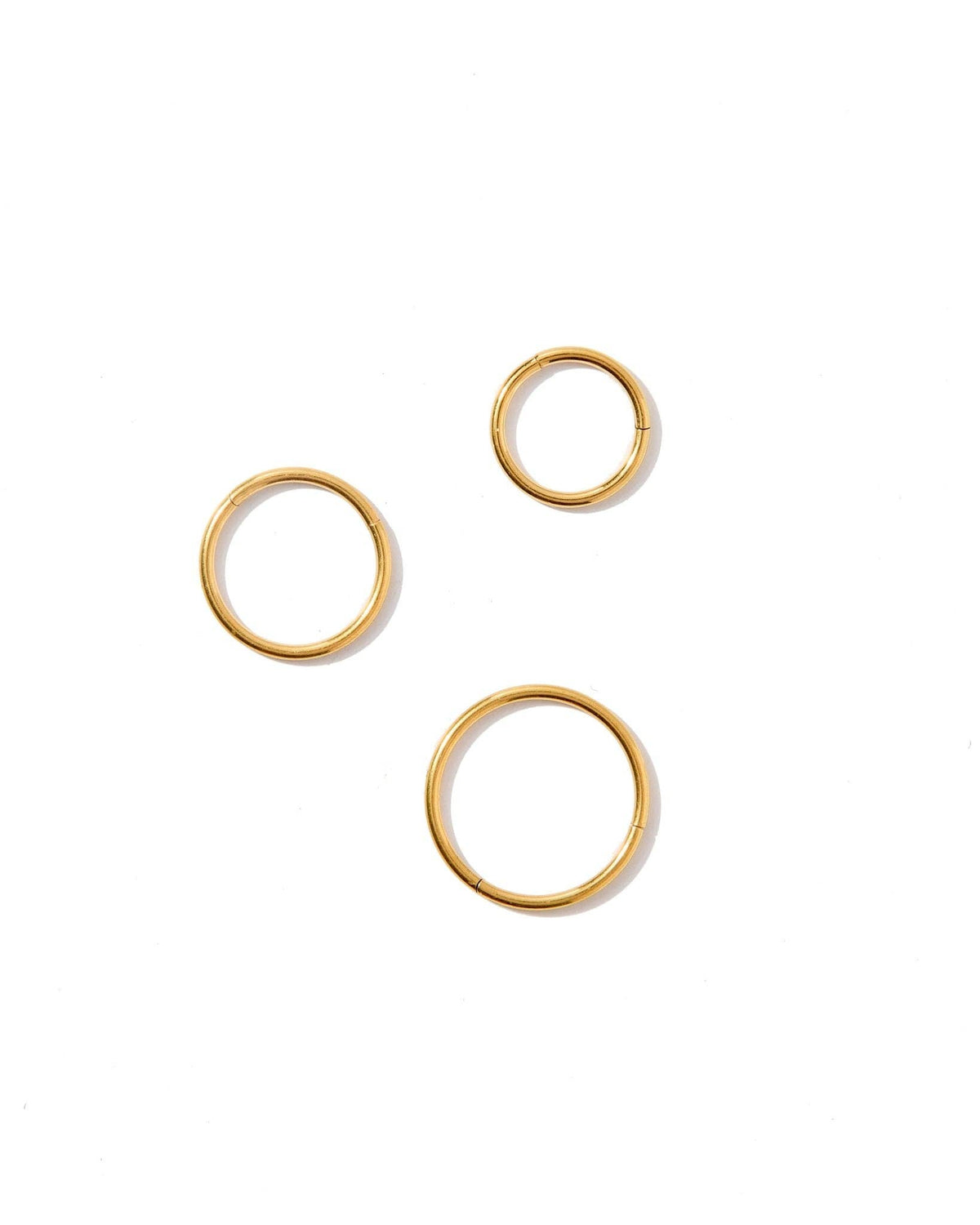 Three gold hoop earrings on a white background