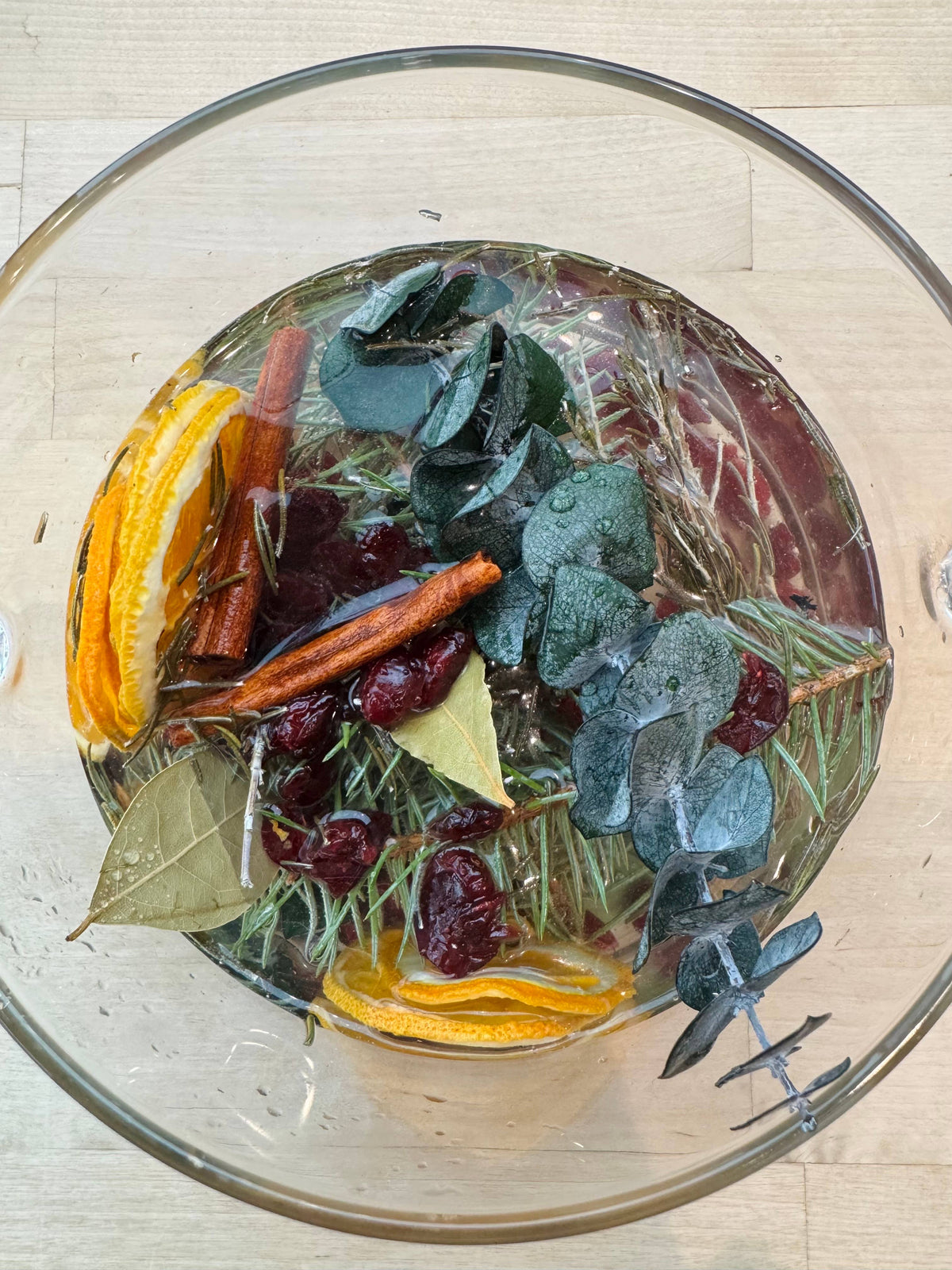 Dried fruits and herbs in a glass bowl on a wooden surface