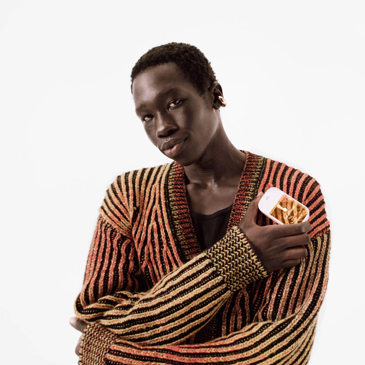 Person wearing a striped sweater holding a touchland hand santizer on a white background