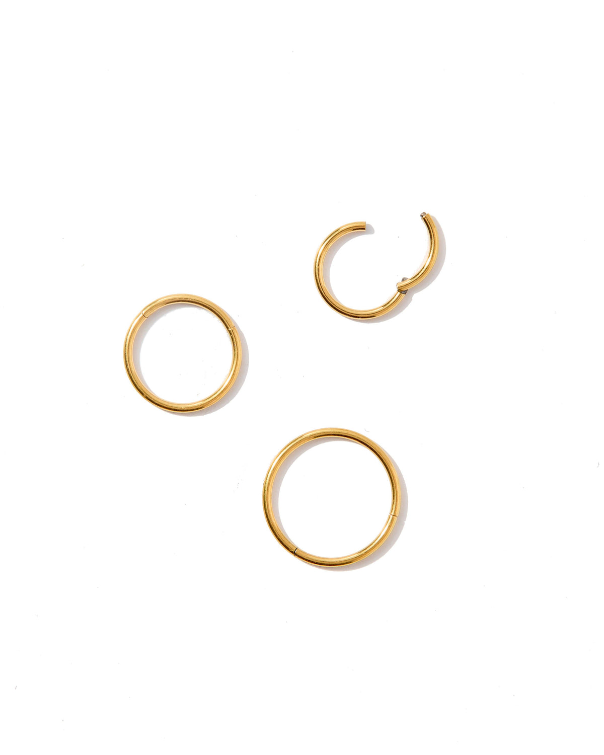 Three gold hoop earrings on a white background