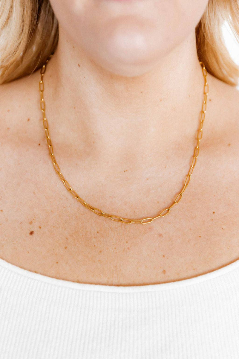 Gold chain necklace on a person wearing a white top